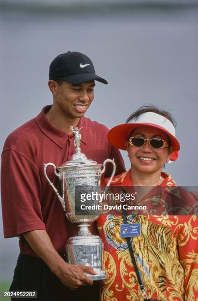 Tiger Woods from the United States stands alongside his mother Kultida Woods holding the United States Golf Association Open Championship trophy...