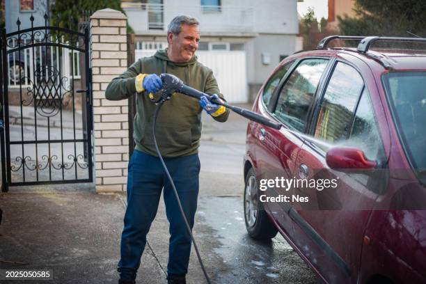 diy, smiling man washes car by himself - car splashing water on people stock pictures, royalty-free photos & images