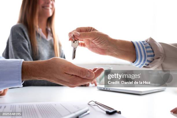 close up image of man and his wife receiving the key for their first apartment at real estate agency after signing contract and buying first home together. - elderly receiving paperwork stock pictures, royalty-free photos & images