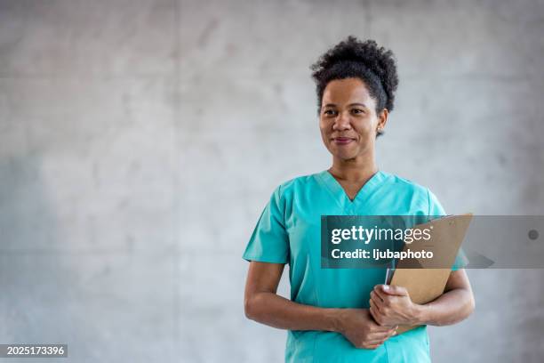 female nurse working at the hospital, holding a clipboard while looking away. - female nurse uniform stock pictures, royalty-free photos & images