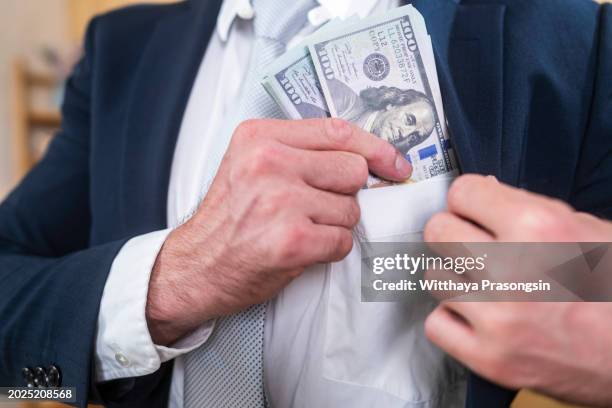 businessman putting money in his pocket - ethical money stock pictures, royalty-free photos & images
