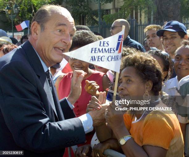 Le président Jacques Chirac serre la main d'une femme qui agite son fanion, "les femmes avec Chirac", lors d'un bain de foule le 17 mai 2001 à...