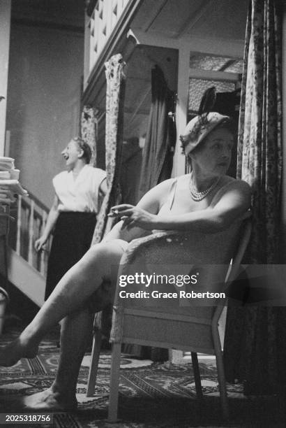 Client smoking a cigarette in the changing room at the Savoy, a women's Turkish bath on Duke of York Street, as another laughs in the back, London,...