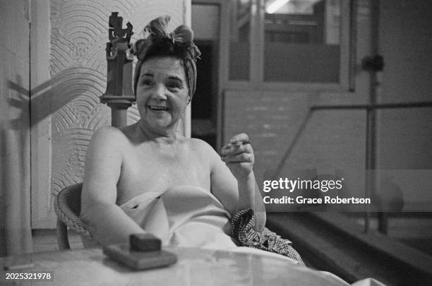 Client smoking a cigarette at the Savoy, a women's Turkish bath on Duke of York Street, London, UK, 1951. Original Publication: Picture Post - 5597 -...