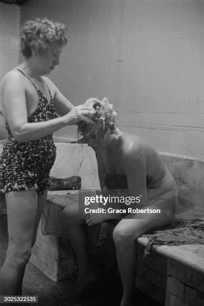 An employee shampooing a client at the Savoy, a women's Turkish bath on Duke of York Street, London, UK, 1951. Original Publication: Picture Post -...