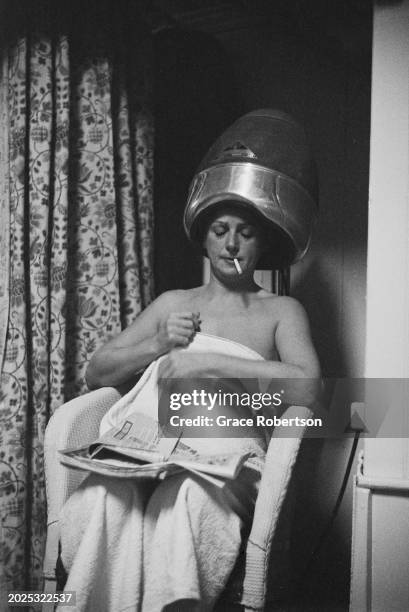 Client smoking a cigarette under a hair hood at the Savoy, a women's Turkish bath on Duke of York Street, London, UK, 1951. Original Publication:...