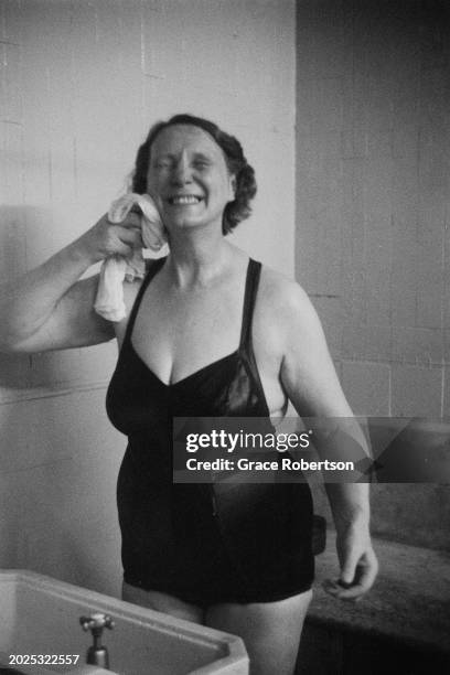 An employee of the Savoy, a women's Turkish bath on Duke of York Street, wipes her face in between jobs, London, UK, 1951. Original Publication:...
