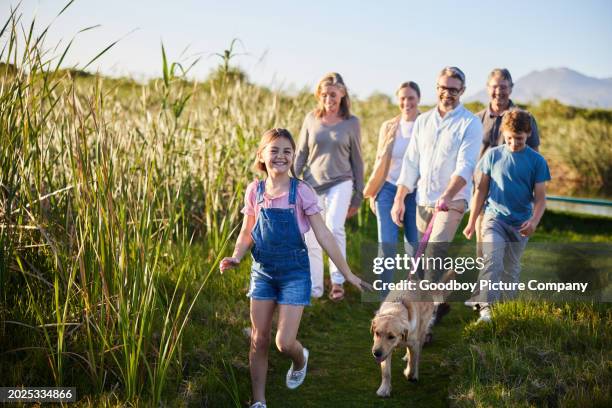 niña sonriente y su familia paseando a su perro en una reserva natural - familia multigeneracional fotografías e imágenes de stock