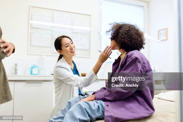 médico revisando la piel de su cliente adolescente - dermatología fotografías e imágenes de stock