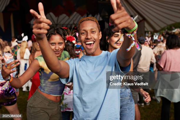 happy man gesturing while dancing with female friends - festival goer stock pictures, royalty-free photos & images