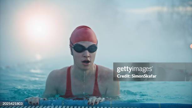 female swimmer wearing swimming goggles and cap in pool on foggy morning - swimming goggles stock pictures, royalty-free photos & images