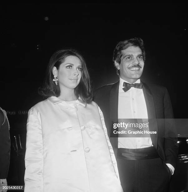 Egyptian actress Faten Hamama, wearing a button-front light coat, and her husband, Egyptian actor Omar Sharif, who wears a tuxedo and bow tie, attend...