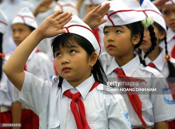 Young girls from the Ho Chi Minh Avant-guard Pionners' Organisation salute during a flag raising ceremony in Hanoi, 19 May 2001, in front of the...