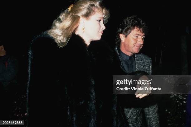 American singer, songwriter and actor Mac Davis, wearing a grey Glen plaid jacket over a grey shirt, and his wife, Lise, who wears a black fur coat,...