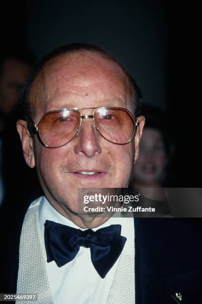 Headshot of American music executive Clive Davis, wearing a black jacket over a white shirt and black bow tie, attends the 10th Annual American...