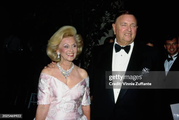 American philanthropist Barbara Davis, wearing a pink-and-white floral pattern off-shoulder evening gown, and her husband, American industrialist...