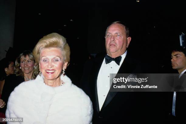American philanthropist Barbara Davis, wearing a white fur coat, and her husband, American industrialist Marvin Davis, who wears a tuxedo and bow...