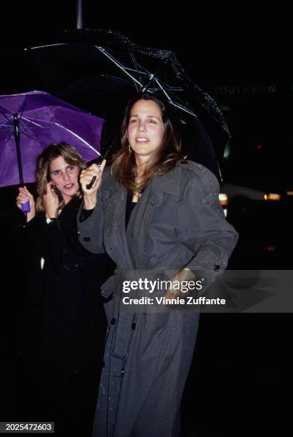 American actress and author Patti Davis, wearing a grey raincoat while sheltering beneath an umbrella attends the Beverly Hills premiere of 'Benny &...