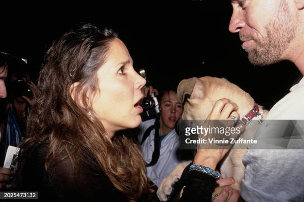 American actress and author Patti Davis, petting a small dog being held by a man, attends the Hollywood premiere of 'Honeymoon in Vegas', held at the...