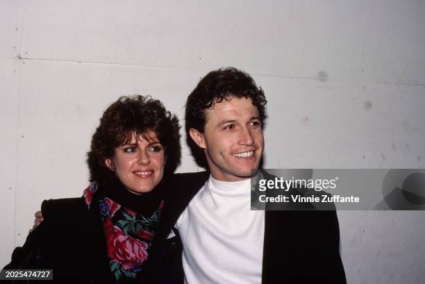 American actress Pam Dawber, wearing a black outfit with a floral pattern scarf, and British singer-songwriter Andy Gibb, who wears a black jacket...