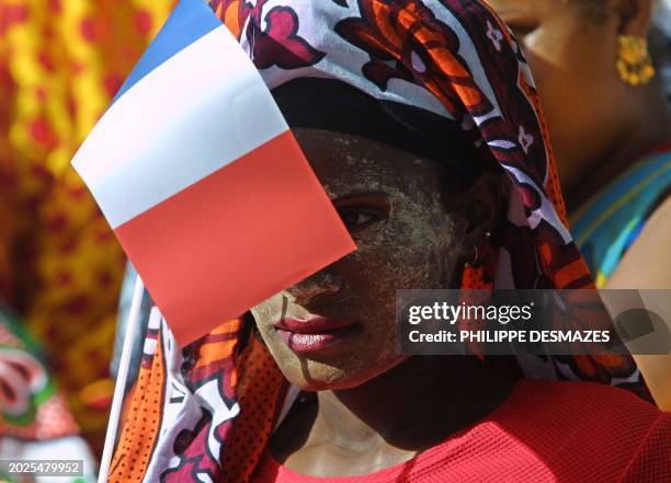 Une jeune femme mahoraise s'abrite du soleil derrière un drapeau tricolore, le 20 mai 2001 dans les rues de Sada, en attendant l'arrivée du président...