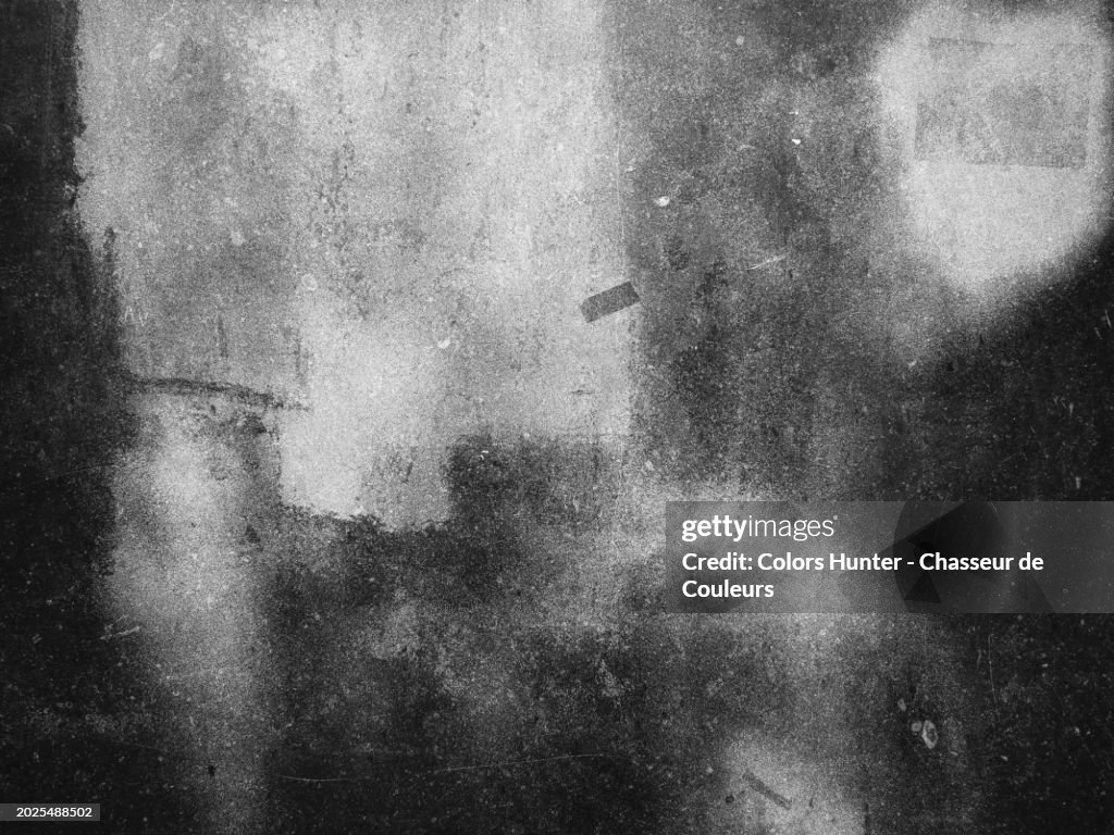 White paint on a gray and dirty stone wall in Brussels, Belgium. Sunlight and shadow. Black and white photograph.