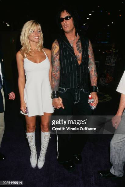 American actress and glamour model Donna D'Errico, wearing a white dress with white knee-high boots, and her husband, American bass player Nikki...