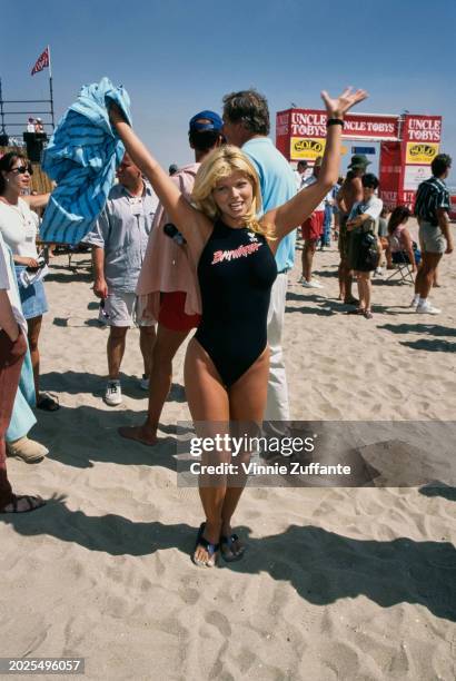 American actress and glamour model Donna D'Errico, wearing a black swimsuit, during a break in filming of 'Baywatch' on Malibu Beach in Malibu,...