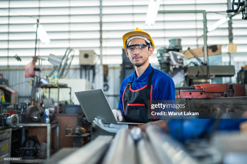 Factory Worker Analyzing Data on Laptop in Workshop