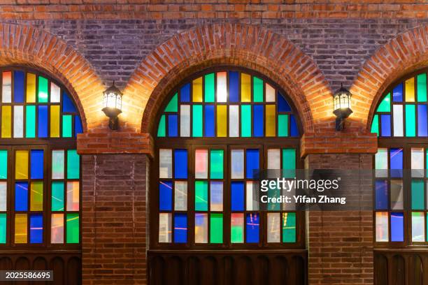 arched stained glass windows on retro brick wall in xijindu ancient street - stained glass door stock pictures, royalty-free photos & images