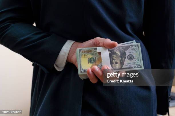 businessman holding money money us dollar behind his back, rear view. - corrupción fotografías e imágenes de stock