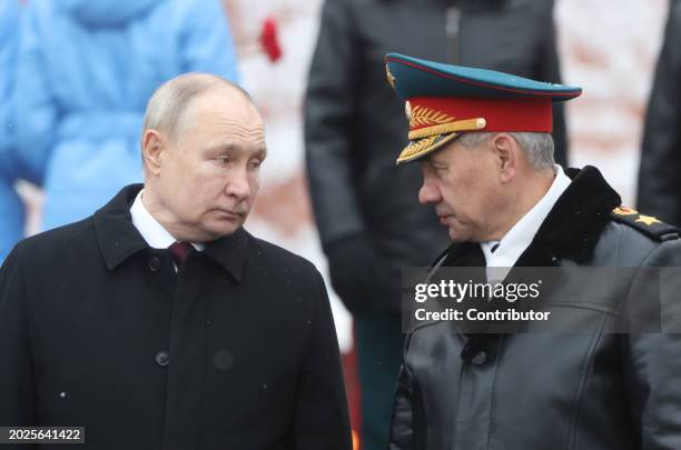 Russian President Vladimir Putin listens to Defence Minister Sergei Shoigu while taking part in the wreath laying ceremony at the Unknown Soldier...