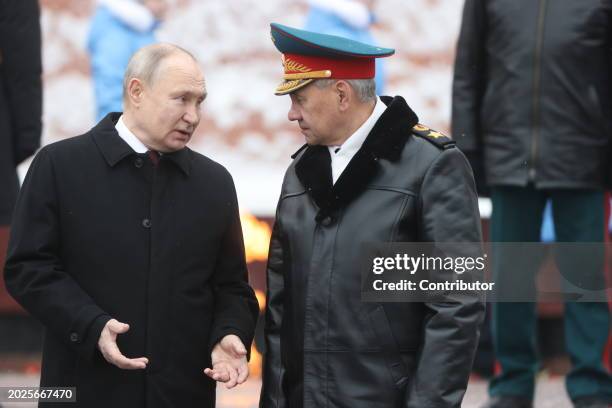 Russian President Vladimir Putin talks to Defence Minister Sergei Shoigu while taking part in the wreath laying ceremony at the Unknown Soldier Tomb,...