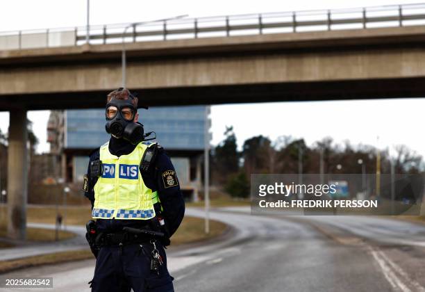 Police officer wearing a gas mask stands guard at the scene after emergency services were alerted to Sweden's Security Service's headquarters in...