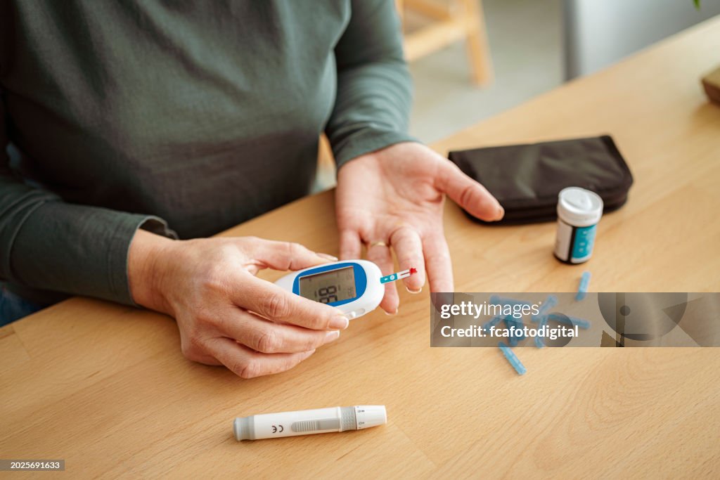 Mulher diabética usando glicosímetro para verificar seu nível de glicose em casa