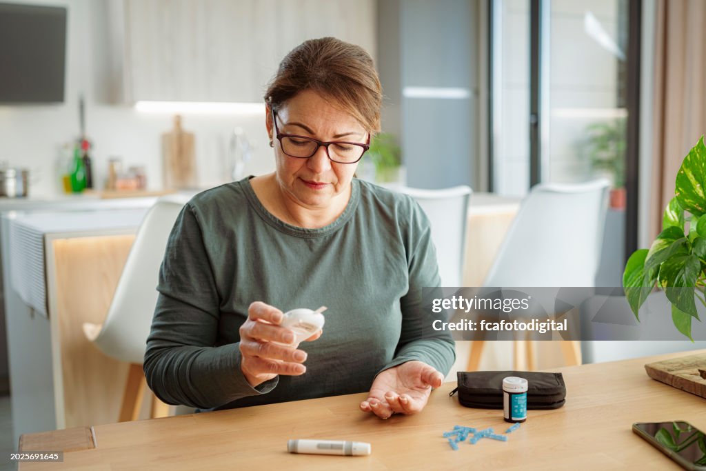 Mature diabetic woman reading glucose level on glucometer
