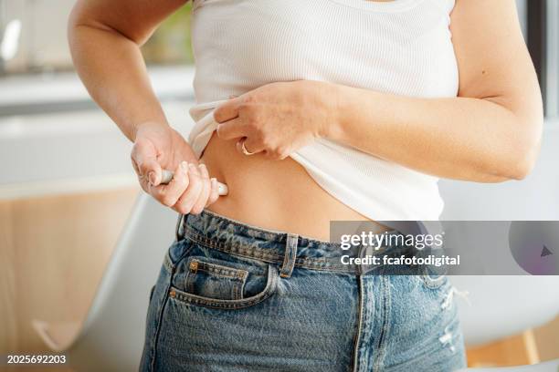 woman injecting insulin in stomach skin - injecting stomach stock pictures, royalty-free photos & images