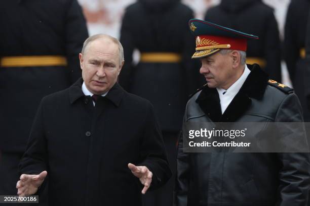Russian President Vladimir Putin listens to Defence Minister Sergei Shoigu while taking part in the wreath laying ceremony at the Unknown Soldier...