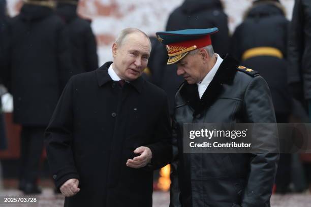 Russian President Vladimir Putin listens to Defence Minister Sergei Shoigu while taking part in the wreath laying ceremony at the Unknown Soldier...