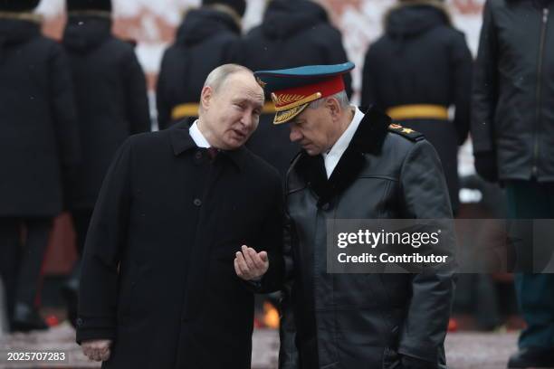 Russian President Vladimir Putin listens to Defence Minister Sergei Shoigu while taking part in the wreath laying ceremony at the Unknown Soldier...