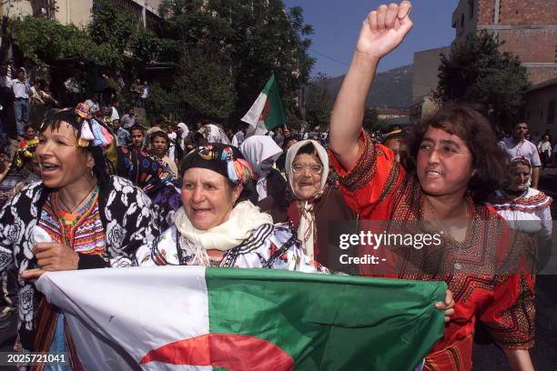 Berber women hold the Algerian flag 24 May 2001 in Tizi Ouzou, capital of the Kabylie region, home to the Berber ethnic minority, during a...