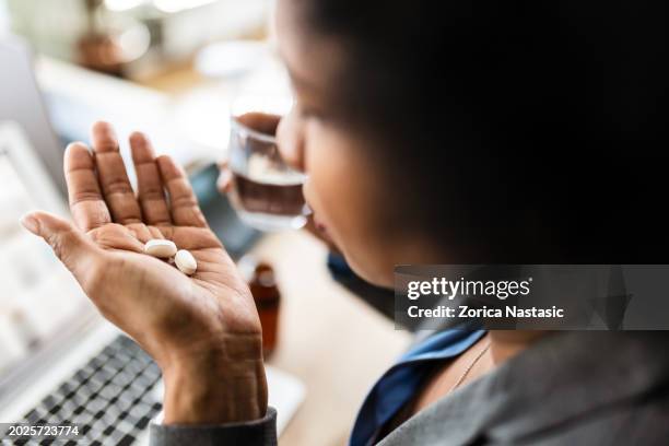 giovane donna afroamericana che prende una pillola - prendere-le-pillole foto e immagini stock