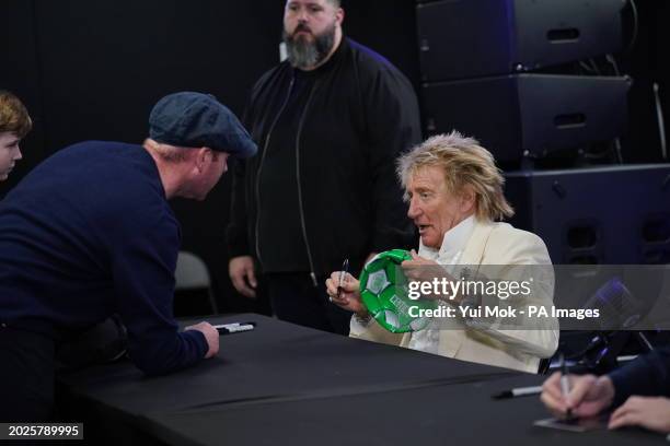 Rod Stewart signs a Celtic FC football during a signing session with Jools Holland for their new collaborative studio album Swing Fever, at HMV...