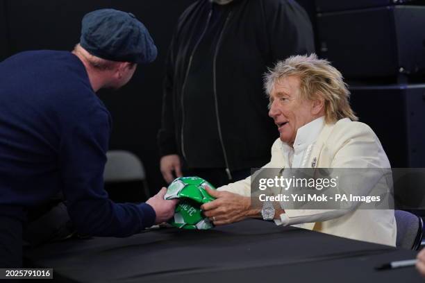 Rod Stewart signs a Celtic FC football during a signing session with Jools Holland for their new collaborative studio album Swing Fever, at HMV...