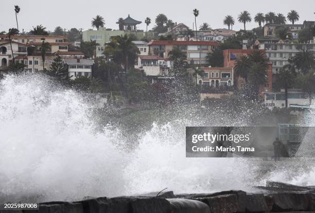 Person takes photos of waves crashing on breakwater rocks at Cabrillo Beach on February 20, 2024 in Los Angeles, California. Another atmospheric...