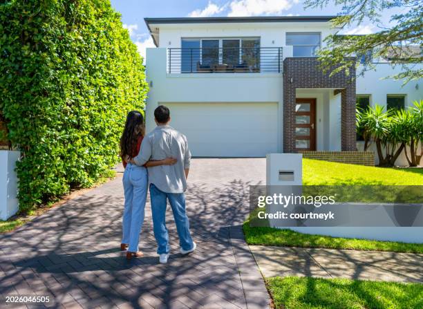 couple heureux debout devant leur nouvelle maison - maison photos et images de collection