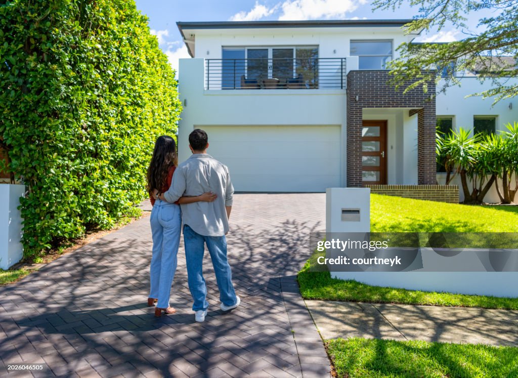 Happy Couple standing in front of their new home