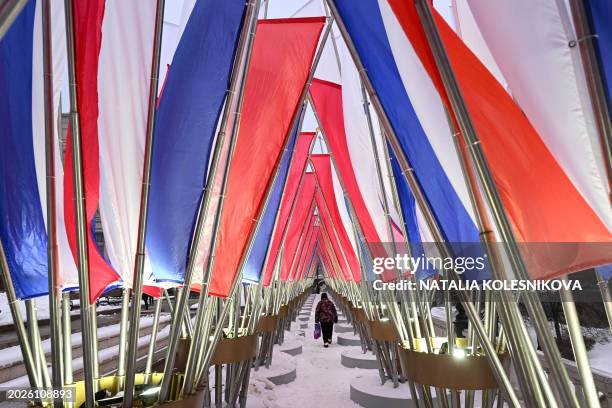 Person walks through decorations in the colours of the Russian national tricolor flag in Moscow on February 23 the Defender of the Fatherland Day.