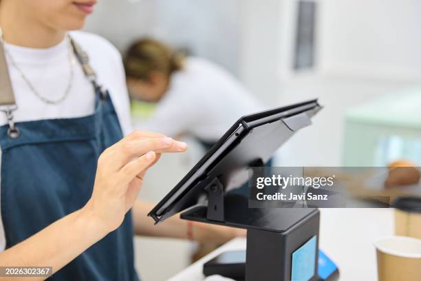 mujer barista irreconocible en el mostrador de la cafetería ingresando el pedido del cliente en una tableta digital. - registrador fotografías e imágenes de stock