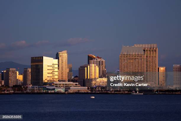 The sun reflects in hotels and residential and commercial high rises in downtown San Diego with San Diego Bay in the foreground on a clear winter...